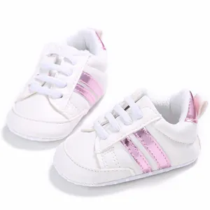 Detalle de zapatos de gateo blancos para bebé con elegantes rayas rosas metalizadas