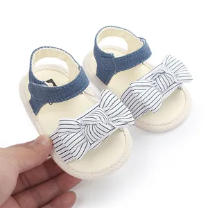 Nahaufnahme weicher Babysandalen mit gestreifter Schleife und blauem Denim-Riemen.