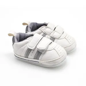 Detailed view of white baby walking shoes featuring dual velcro straps and side stripes