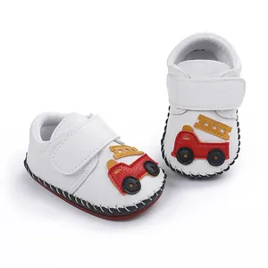Gros plan de chaussures de marche blanches pour bébé avec un joli camion de pompier.