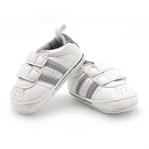 Detailed close-up of white baby walking shoes featuring non-slip rubber soles and stripes.