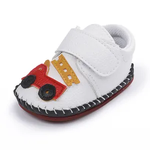 Vue détaillée d'une chaussure pour bébé blanche avec un motif de camion de pompiers.
