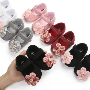 Detalle de zapatos para bebé niña con adornos florales y suela blanda en varios colores.
