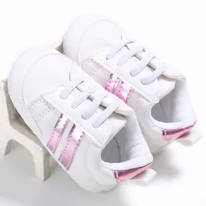 Detalle de zapatillas blancas para bebé con rayas rosas y suela blanda