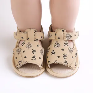 Detail view of beige baby sandals featuring black tree and star patterns on the fabric.
