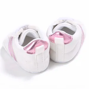 Vista trasera de zapatos blancos para caminar de bebé con parches de talón rosa metálico