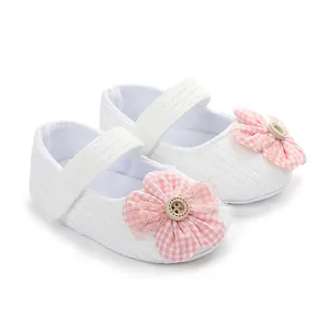 Vista detallada de zapatos blancos para bebé con flor de cuadros rosa y botón