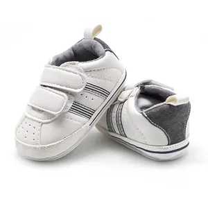 Detail of white baby walking shoes with non-slip rubber sole and velcro straps.