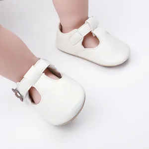 Close-up of white baby girl princess shoes with flower detail and soft T-strap closure.