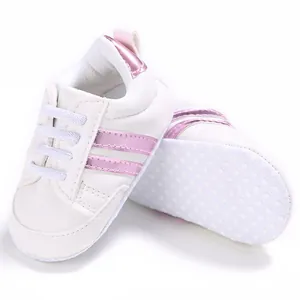 Primer plano de zapatos de bebé blancos con rayas rosas y suela blanda antideslizante