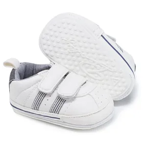 Close-up of white baby walking shoes with two stripes and non-slip rubber soles