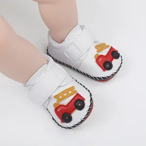 Vue détaillée des chaussures de marche bébé blanches avec motif camion de pompiers