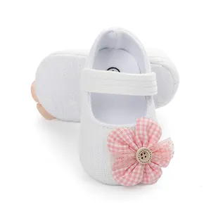 Detail view of white baby princess shoes with a pink gingham flower and soft non-slip sole