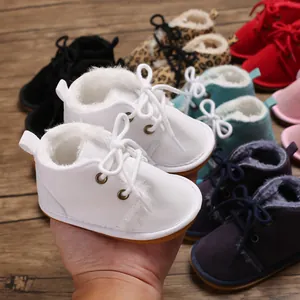 Nahaufnahme weißer, plüschgefütterter Babyschuhe mit bunter Vielfalt im Hintergrund.