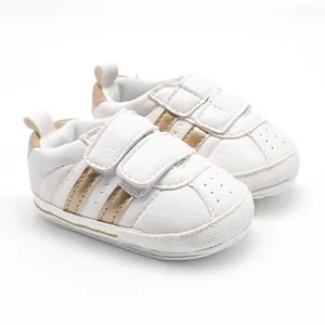 Close-up of comfortable white baby walker shoes featuring gold stripes and velcro straps