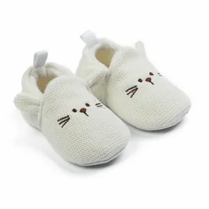 Close-up of white knitted baby walking shoes with cute cat face embroidery