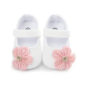 Detalle de zapatos blancos de bebé con flor de cuadros rosa y decoración de botón