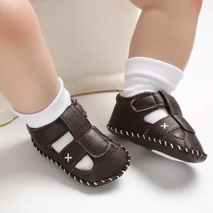 Nahaufnahme von braunen Baby-Sommersandalen mit weißen Nähten an Babyfüßen