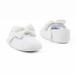 Close-up of white knitted baby princess shoes with large bow details
