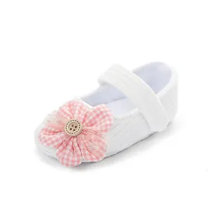 Detalle de la flor de cuadros rosas y el botón de madera en el zapato de bebé