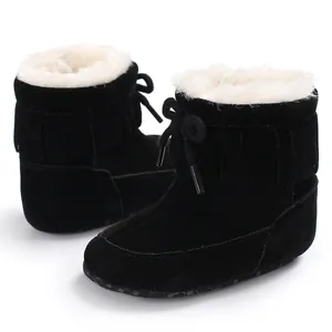 Close-up of black baby winter snow boots with soft white faux fur lining and fringe