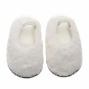 Vista dall'alto di morbide babbucce per neonati in peluche bianco con cinturini elastici.