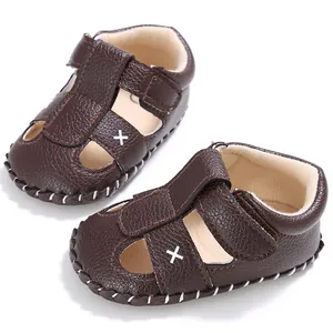 Nahaufnahme von braunen Baby-Sandalen aus Kunstleder mit Klettverschluss und Kreuzdekor
