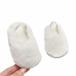 Dettaglio di scarpine per neonati in peluche bianco con cinturino