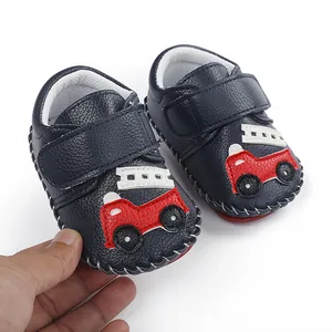 Vue détaillée des chaussures pour bébés bleu marine avec applique camion de pompiers.