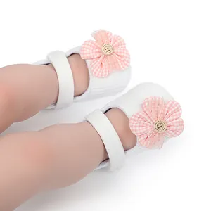Close-up of white baby walker shoes with pink checkered flower and wooden button detail