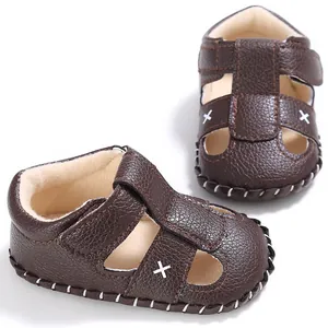 Nahaufnahme von braunen Baby-Sandalen aus Leder mit weißen dekorativen Kreuzstichen