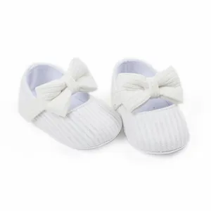 Close-up of white ribbed knit baby girl Mary Jane shoes with large decorative bow