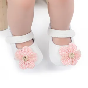 Primer plano de zapatos blancos para bebé niña con flores de tela a cuadros rosas