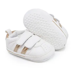 Detailed view of white baby walking shoes with gold stripes and anti-slip rubber sole