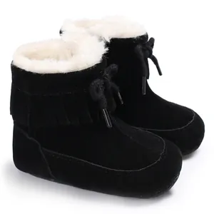 Side detail of black baby winter snow boots with white faux fur lining and fringe decorations.