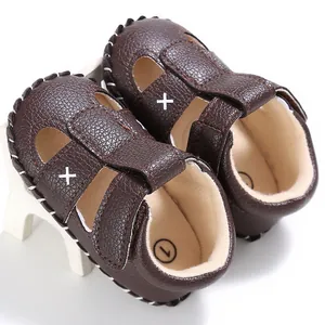 Makrodetail dunkelbrauner Baby Sommer Lauflernsandale mit weißer Kreuzstickerei und Ziernähten