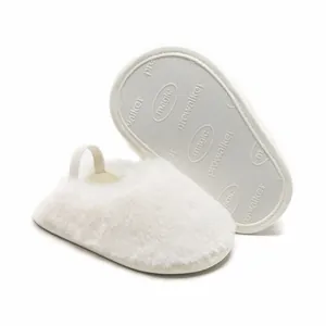Dettaglio delle babbucce per neonati in peluche bianco che mostrano la suola morbida