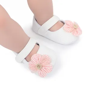 Detail of soft white baby princess shoes with pink gingham flower decoration