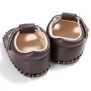 Detailaufnahme dunkelbrauner Baby-Lauflern-Sandalen mit eleganten weißen Ziernähten.