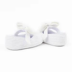 Detailed side view of white ribbed fabric baby pre-walker shoes with a large bow