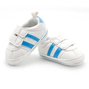 Detail of infant sports walking shoes in white with blue stripes and velcro straps
