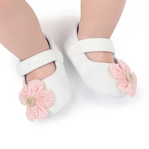 Detailed close-up of white soft-soled baby Mary Jane shoes with pink checkered flower décor.