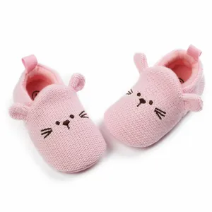 Close-up of pink knitted baby walking shoes with cute cat embroidery and soft ears.
