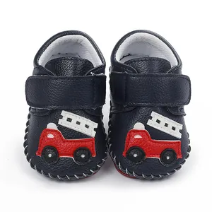 Détail de chaussures de marche pour bébé bleu marine avec motif de camion de pompiers rouge.