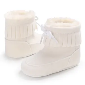 Close-up of white baby snow boots with soft faux fur lining and tassel detail.