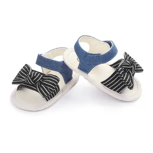 Nahaufnahme von weichen Babysandalen mit blauem Jeansriemen und gestreifter Schleife