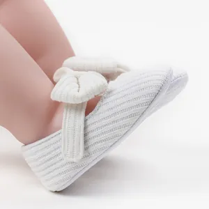 Nahaufnahme von weiß gestrickten Baby-Prinzessin-Schuhen mit weichem Schleifenband