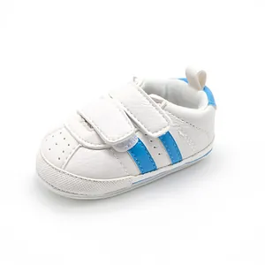 Detailed side view of white baby walking shoes with blue stripes and velcro straps