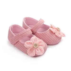 Detalle de zapatos rosa para bebé niña con flor a cuadros y decoración de encaje.