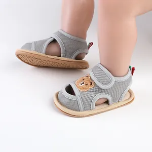 Nahaufnahme von grauen, atmungsaktiven Baby-Lauflernsandalen mit Bärenstickerei.